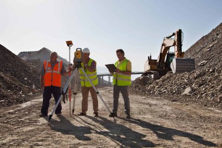 Image-of-construction-workers-leveling-a-site-with-an-excavator-in-the-background